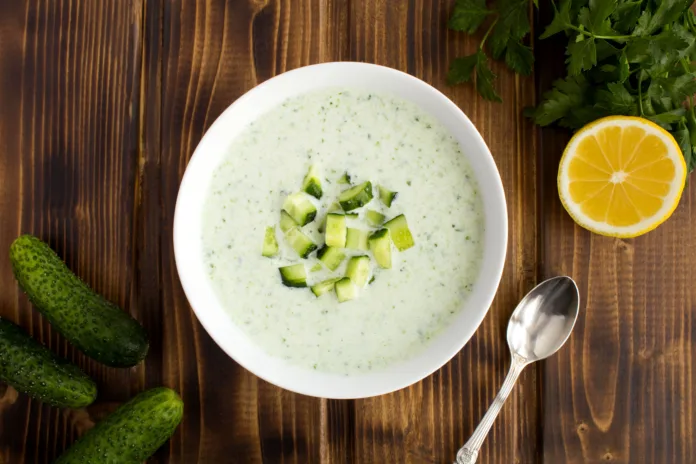 Yogurt smoothies  with  cucumber in the white bowl  on the brown wooden background.Top view. Close-up.