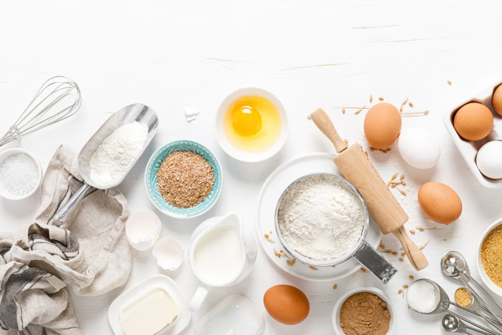 Baking homemade bread on white kitchen worktop with ingredients for cooking, culinary background, copy space, overhead view