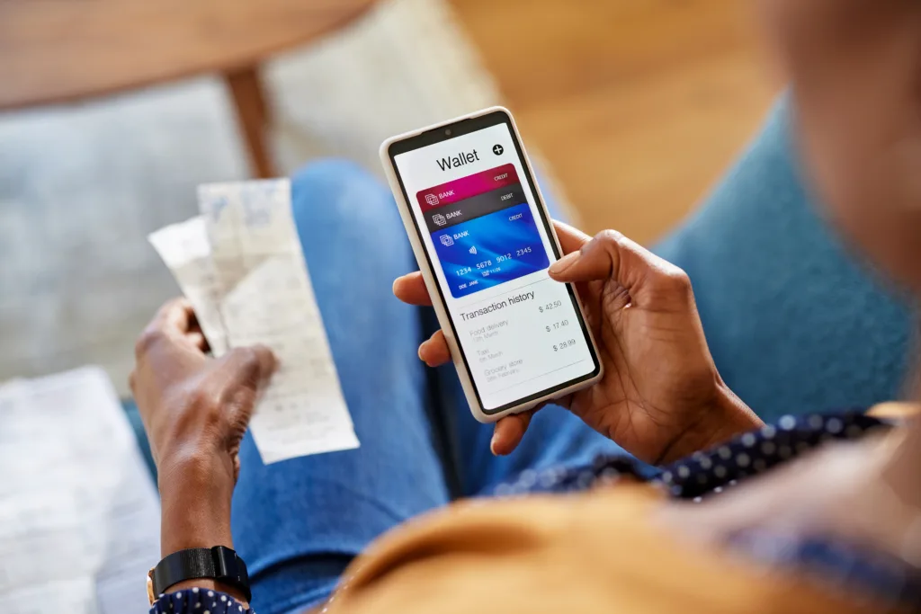 Hands of african american woman using mobile phone to check payments, account statement and transaction history. Close up of black woman hand using smartphone for checking the balance of her online wallet. Checking expenses of the month on smart phone by internet banking.