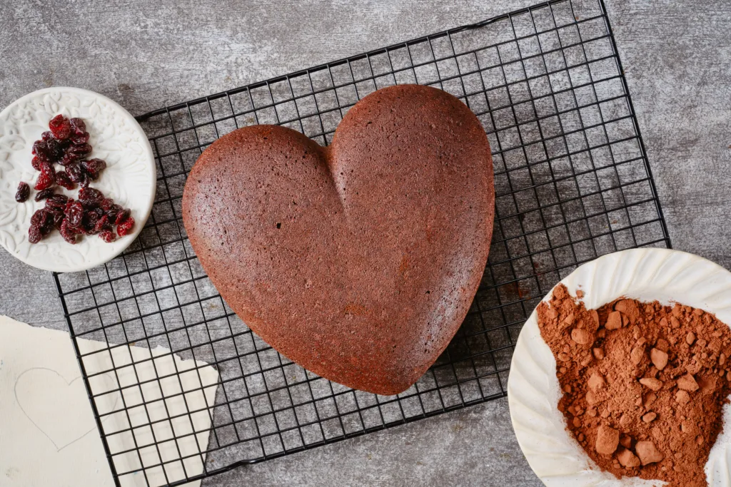 Muffin or bundt cake in the shape of a heart on a bake grid on a gray grunge background. Christmas Stollen traditional European festive dessert. Flat lay