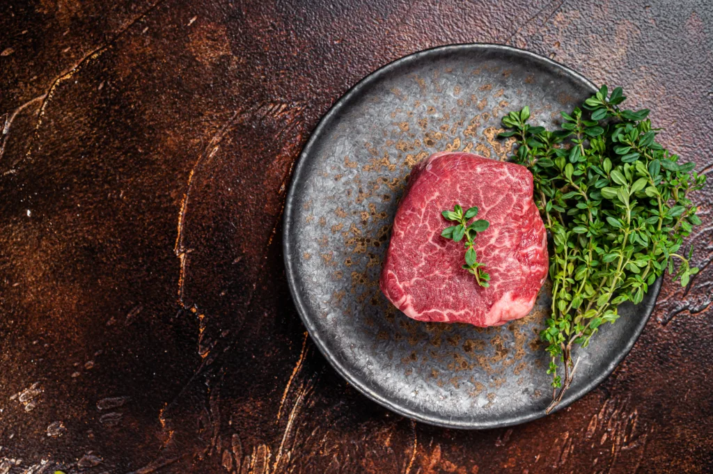 Prime Fillet Mignon Beef steak, Dry aged raw tenderloin meat. Dark background. Top view. Space for text.