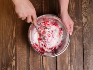 Raspberry ice cream with berries and mint, served in glasses on an old wooden desk