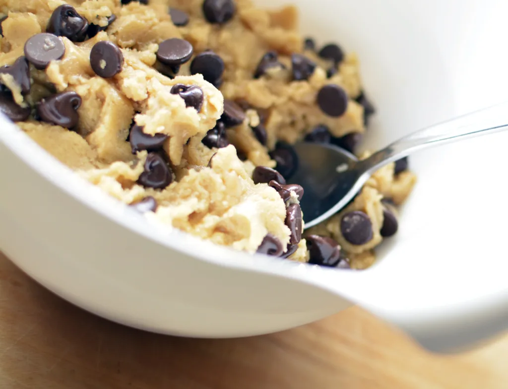 Raw cookie dough in a white mixing bowl with spoon