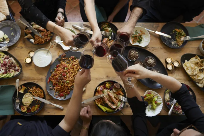 richly set dinner table from above with hands eating drinking and toasting