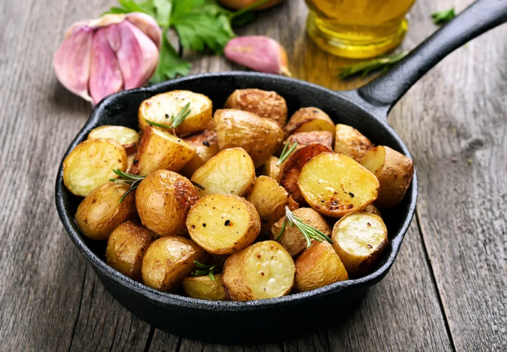 Roasted potato in frying pan on wooden background