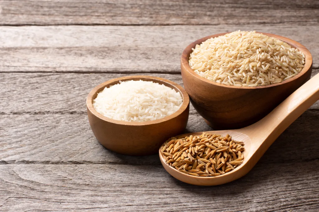 Set of raw rice ; paddy rice, brown coarse rice and white thai jasmine rice in wooden bowl isolated on wooden table background.