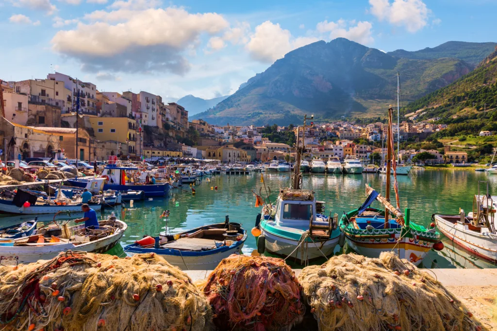 Sicilian port with fishing boats of Castellammare del Golfo village of Sicily, Trapani, Italy. Castellammare del Golfo town (Gulf of Castellammare) on Mediterranean Sea, Trapany, Sicily, Italy.