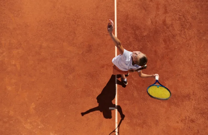 Top view of a professional female tennis player serves the tennis ball on the court with precision and power.