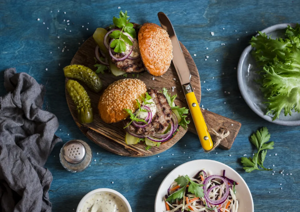 Two homemade burgers on a wooden cutting board, top view. Flat lay