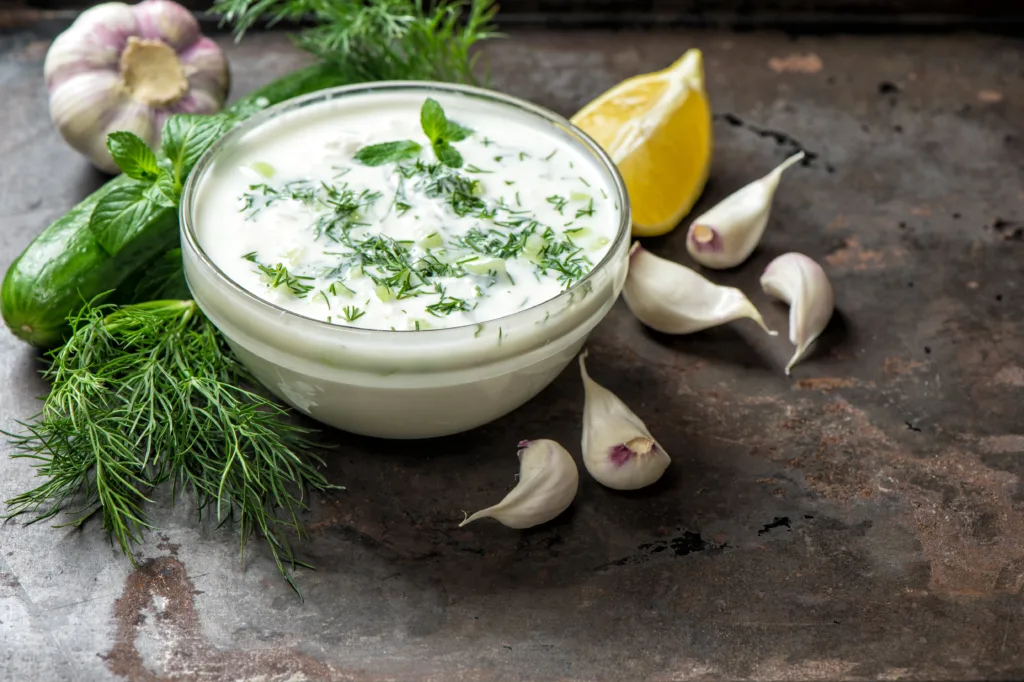 Tzatziki sauce with ingredients cucumber, garlic, dill, lemon, mint. Healthy food background