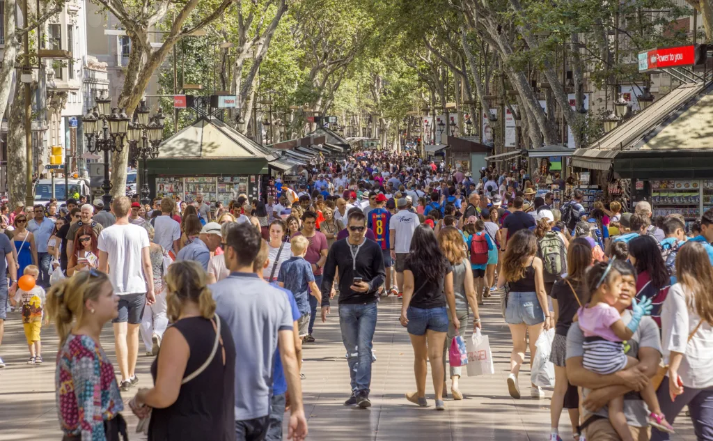 Barcelona, Spain - July 5, 2016: Hundreds of people promenading in the busiest street of Barcelona, the Ramblas. The street extends 1.2 kilometers connects the Placa de Catalunya in the centre with the Christopher Columbus Monument at Port Vell.