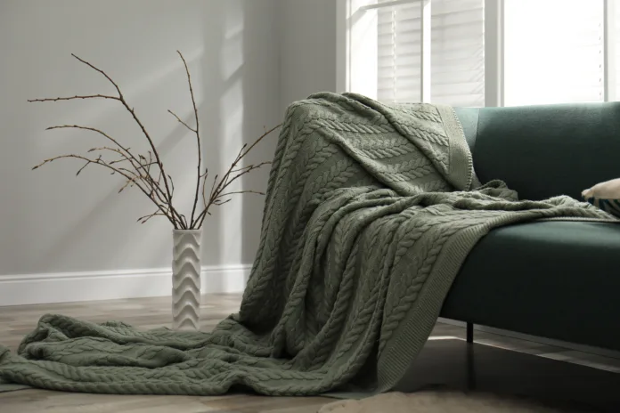 Beautiful tree twigs in vase on floor near sofa indoors