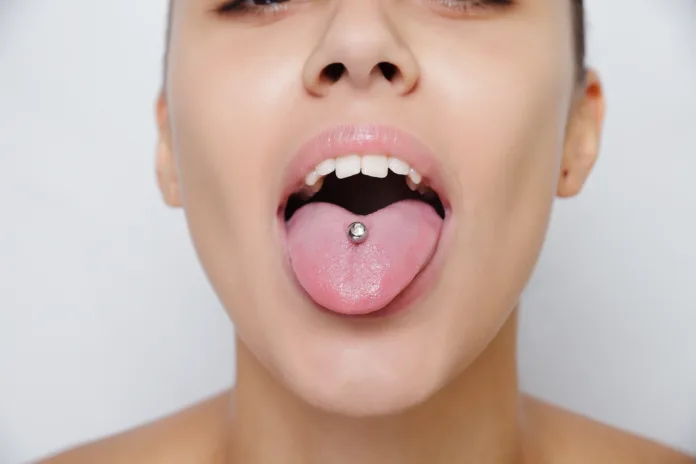 Beautiful woman sticking out her tongue and showing her young piercing