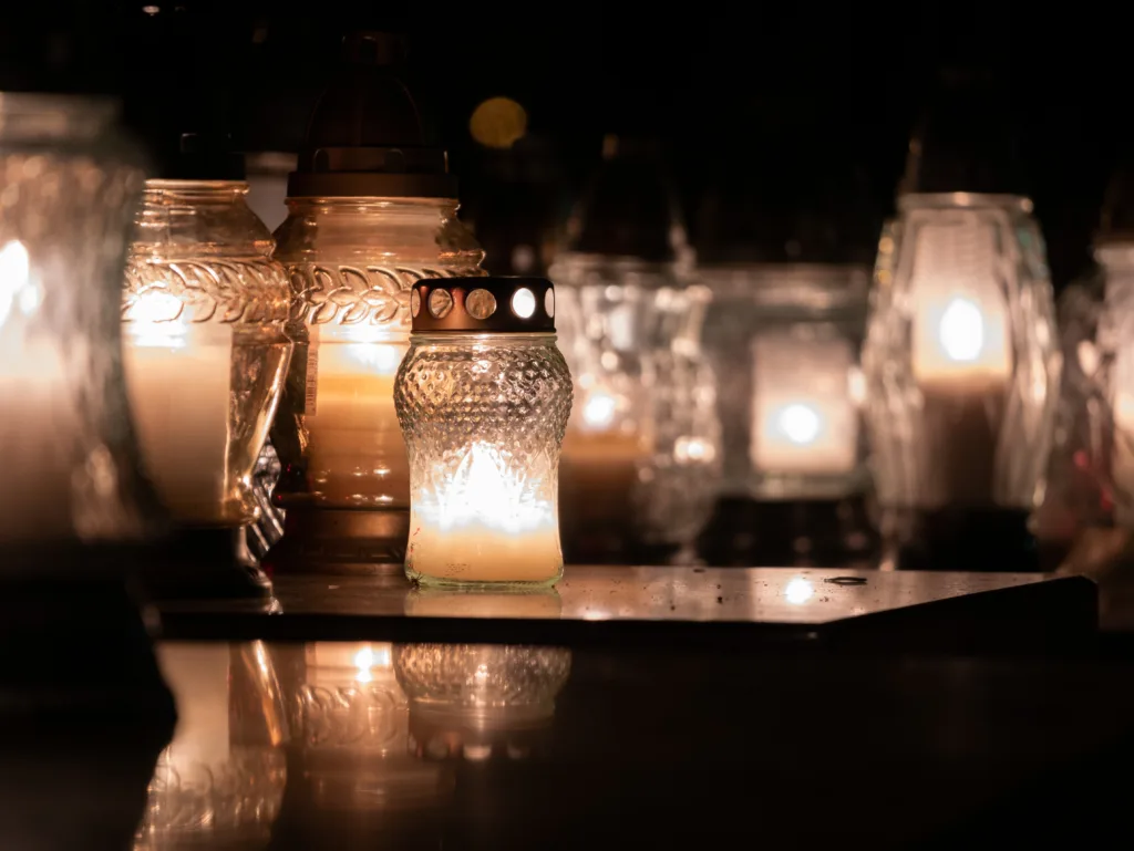 Cemetery grave candle glass lanterns illuminated at night. All Saints' Day, Feast of All Souls. Commemoration of All the Faithful Departed and the Day of the Dead.