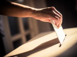 Conceptual image of a person voting, casting a ballot at a polling station, during elections.