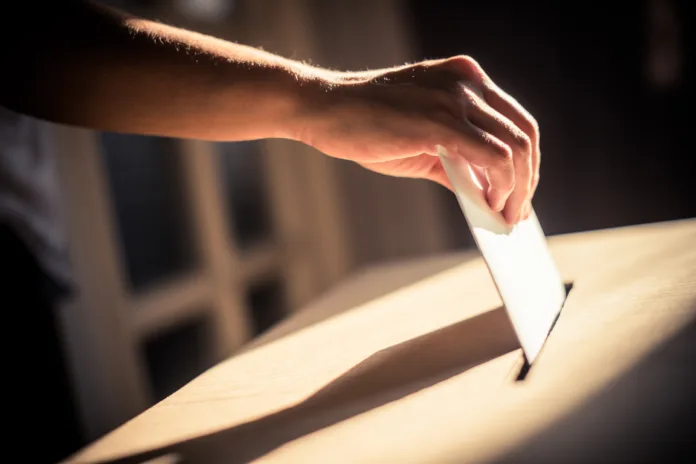 Conceptual image of a person voting, casting a ballot at a polling station, during elections.