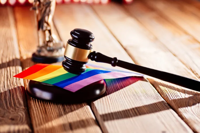 Judge wooden mallet - symbol of law and justice with lgbt rainbow colours flag. Lgbt rights and law