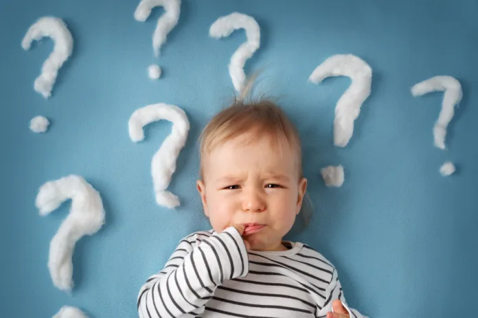 little boy lying on blue blanket with lots of question marks