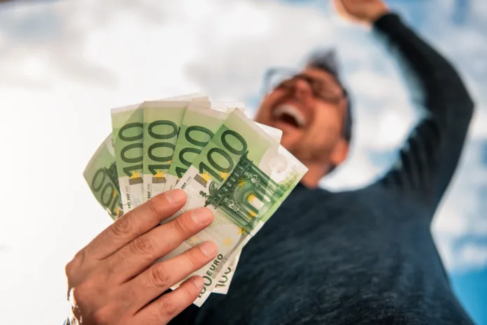 Man with glasses wearing blue shirt. and holding stack of money.