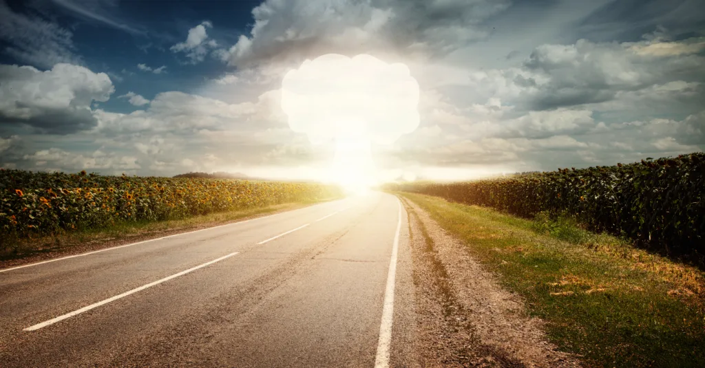 Nuclear explosion in an outdoor setting with blue sky cloud and sunflower field. Dangers of nuclear energy