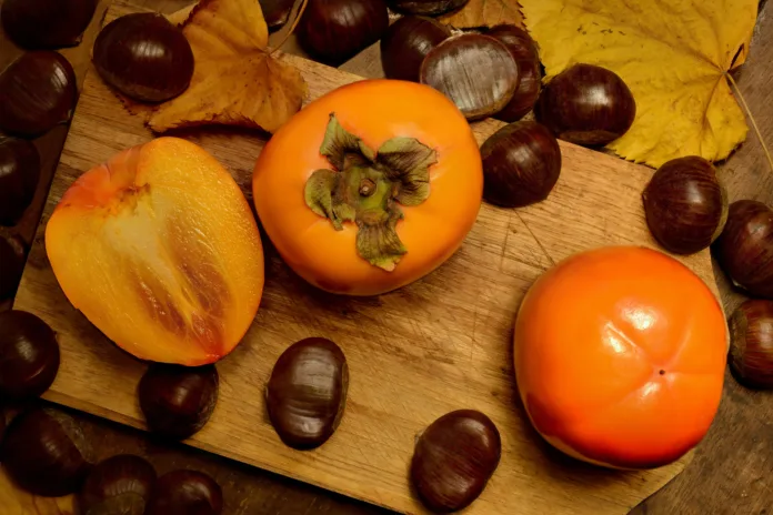 Persimmons and chestnuts on a cutting board