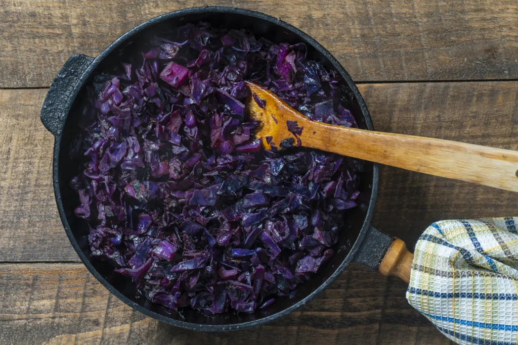 Red cabbage are pan-fried until lightly charred, then braised in mulled wine. Background of fry blue cabbage in a section, macro. Close up, top view. Texture and pattern of purple cabbage