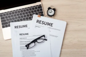 Resumes on laptop with glasses on wood desk, resume review, job interview, top view