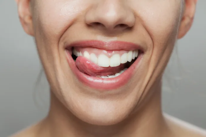 A close-up image capturing a happy woman licking her lips, showcasing healthy teeth and expressing joy and satisfaction. Perfect for dental hygiene promotions.