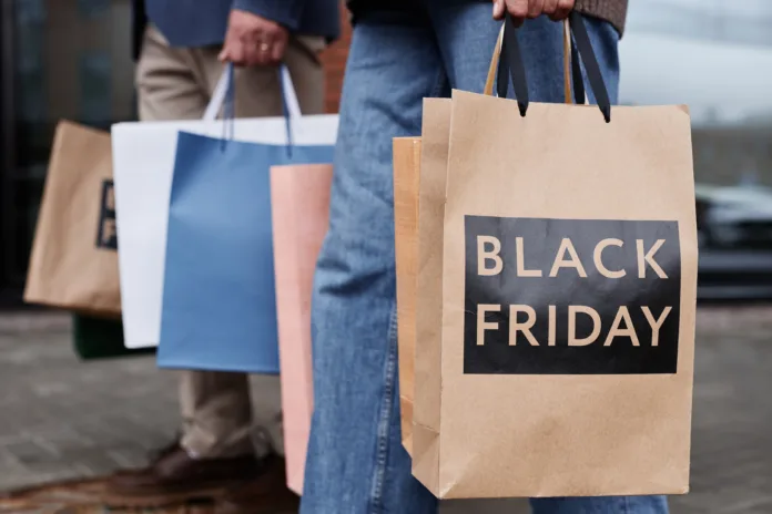 Close up of couple holding Black friday shopping bags walking together outdoors