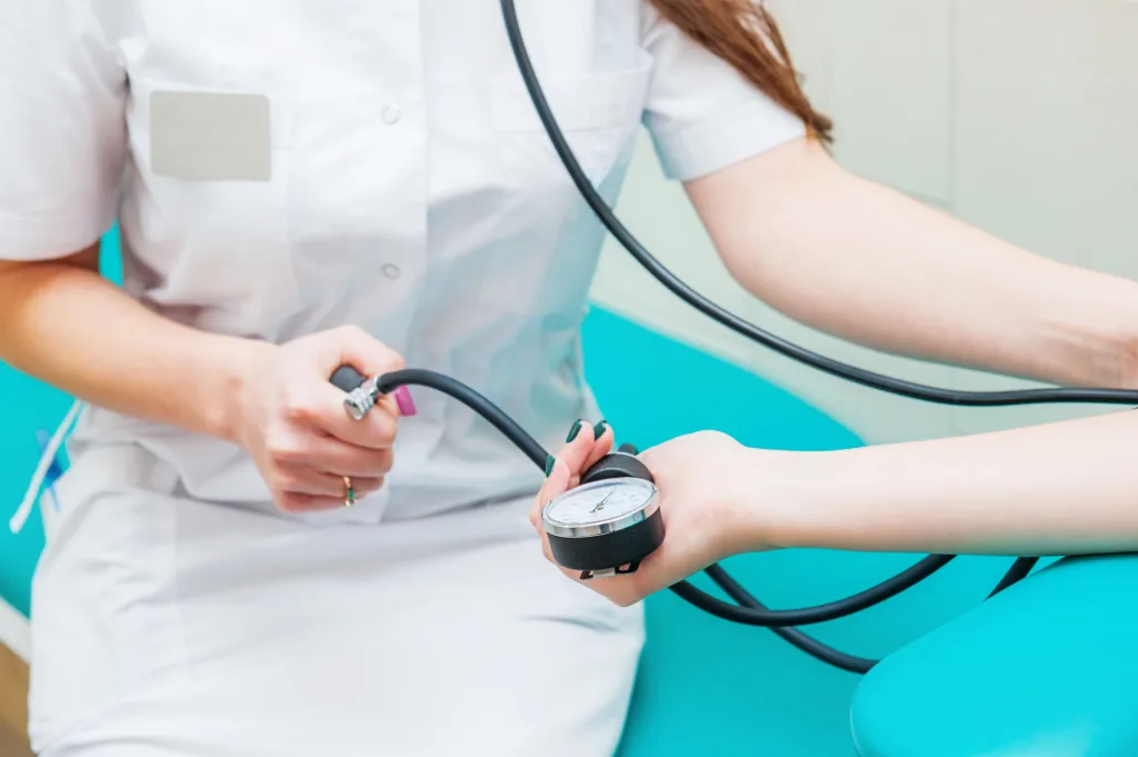 Close up view of female medicine doctor measuring blood pressure to her patient. Hands close up. Healthcare, healthy lifestyle and medical service concept.