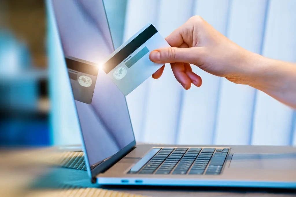 female hand with credit card and online payment using laptop. the hand with the card touches the laptop monitor