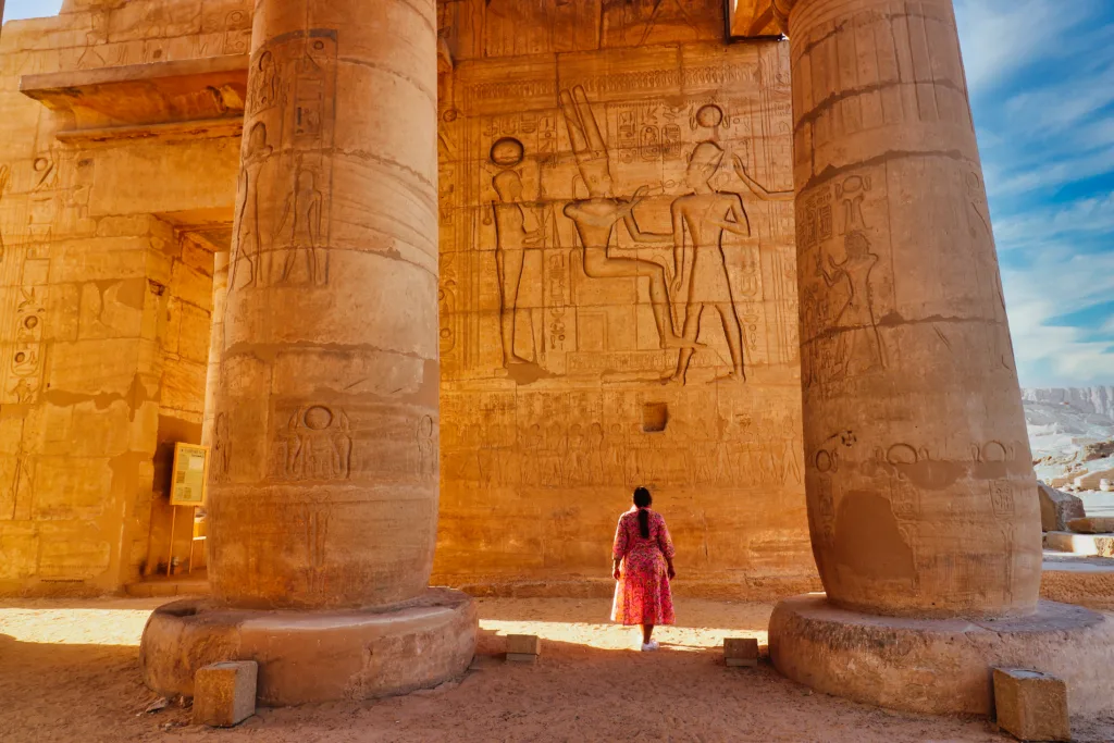 Luxor,Egypt,January 1,2020-A visitor admires the wall relief of Ramesses II receiving blessings from Amun and Ptah at the end of the main hypostyle gallery at the mortuary temple of Ramesseum