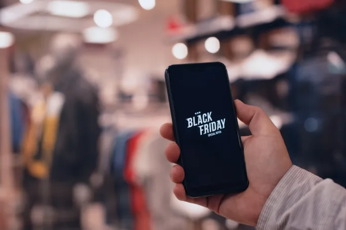 Online shopping on Black Friday. A man holds a smartphone in his hands against the background of a fashionable clothing boutique