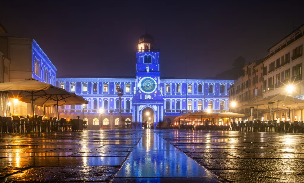 Padua, Italy - December 14, 2023: Piazza dei Signori in the evening, in the background the palace with the clock tower. Lights with Christmas decorations are projected on the facade.