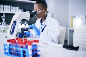 Science, laboratory and woman on microscope for blood test research, medical analysis and dna or virus test. Biotechnology, test tube and scientist or doctor or person with lens check for particles