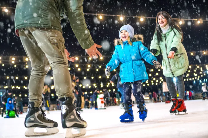 Skating rink. Happy family on the ice rink. Mom and dad teach daughter to skate.