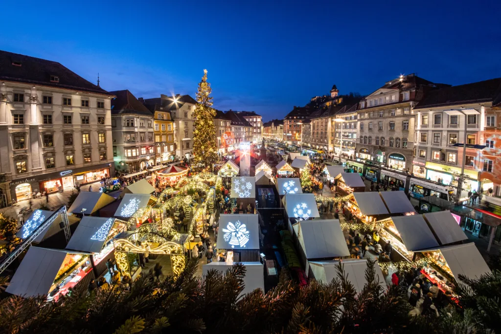 View from city hall Rathaus to Christmas market Christkindlmarkt on main square with landmark Uhrturm in Graz, Styria, Austria