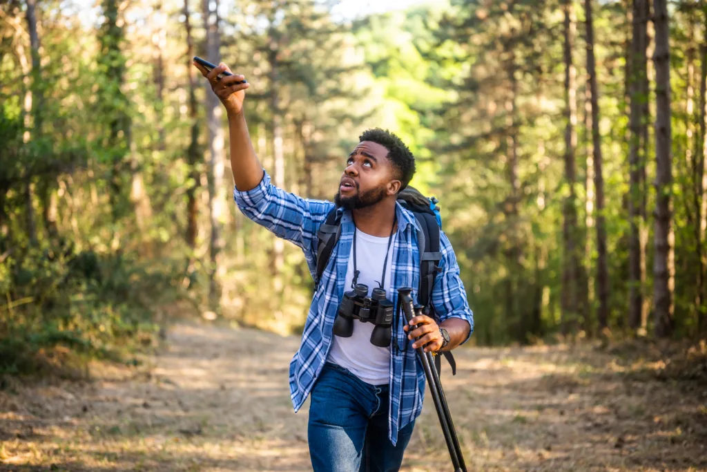 Young hiker is searching signal for mobile phone in nature.