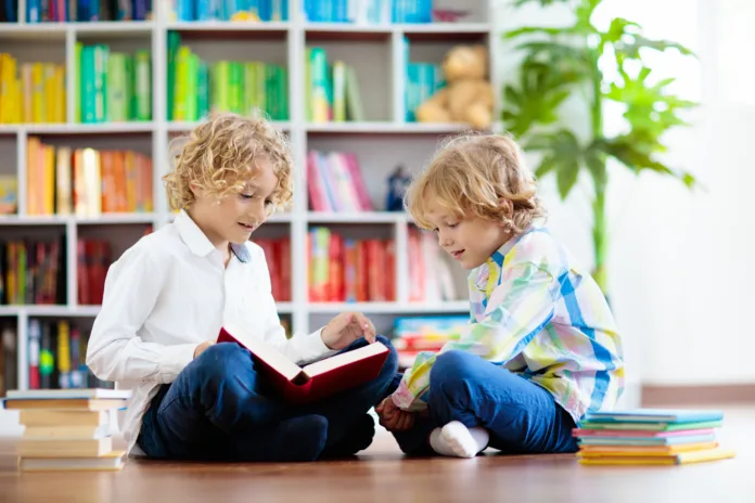 Child reading book. Kids read. Little boy at a colorful bookshelf doing homework for school. Student with books. Early education and development. Home library for children. Preschool kid study.