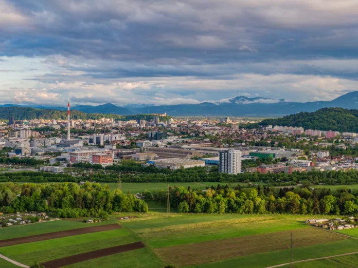 DRONE: Flying towards industrial-residential neighborhood of Šiška, Ljubljana on a cloudy summer afternoon. Dark stormy clouds gather above an urban neighborhood in the capital city of Slovenia.