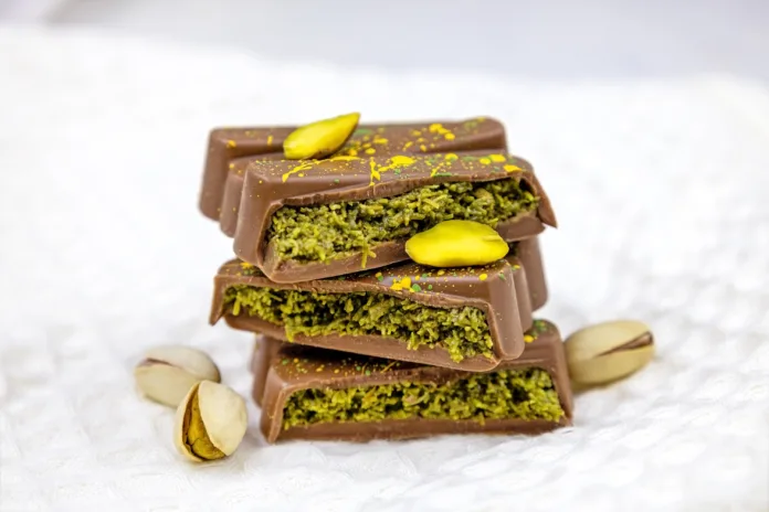 Dubai Chocolate bar with green kadayif and pistachio spread with pistachio nuts close up