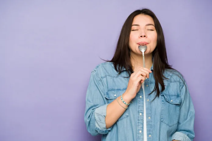 Gorgeous caucasian woman in her 30s eating delicious food with a spoon and enjoying dessert