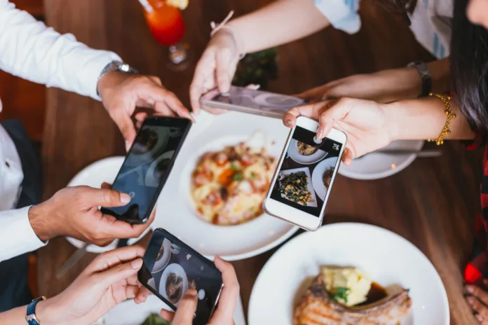 Group of friends going out and taking a photo of Italian food together with mobile phone