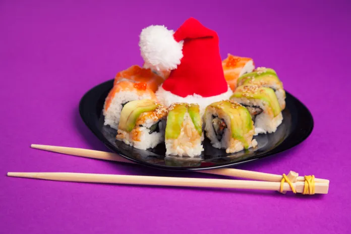 Maki sushi on purple background with santa hat