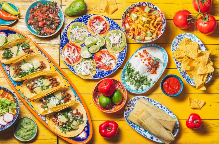 Mexican festive food for independence day - independencia chiles en nogada, tacos al pastor, chalupas pozole, tamales, chicken with mole poblano sauce. Yellow background