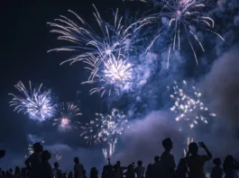 New Year's celebration on the beach. People watching the fireworks at the water's edge.