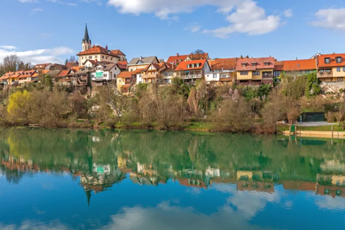 Novo Mesto, Slovenia - March 6, 2020: Houses Reflection at Calm Surface of River Krka Clear Winter Day in Town.