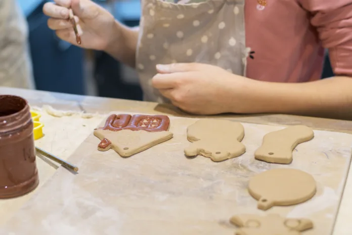 Production of ceramic Christmas toys. The child's hands glaze the domili and clay Christmas trees. Christmas Souvenirs, Selective Focus