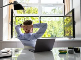 Relaxed Young Businessman Relaxing On Chair Behind Desk At Office