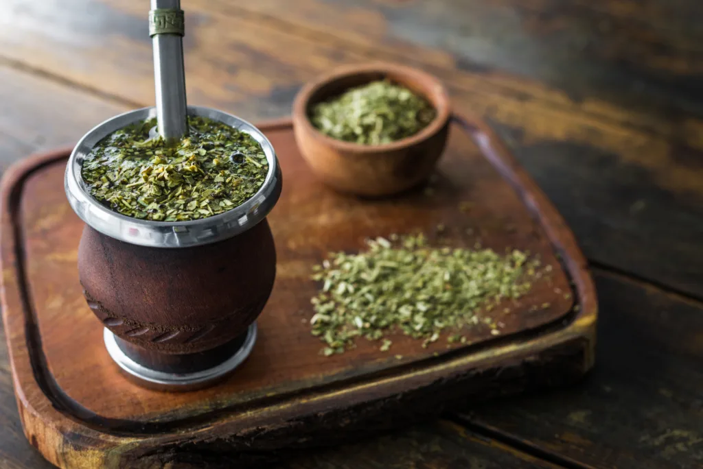 Traditional Argentinian yerba mate tea in a calabash gourd with bombilla stick against wooden background